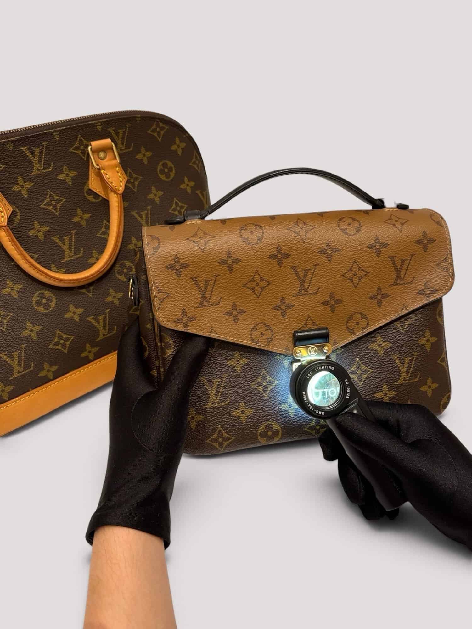 Gloved hands examining handbag details with a magnifying glass